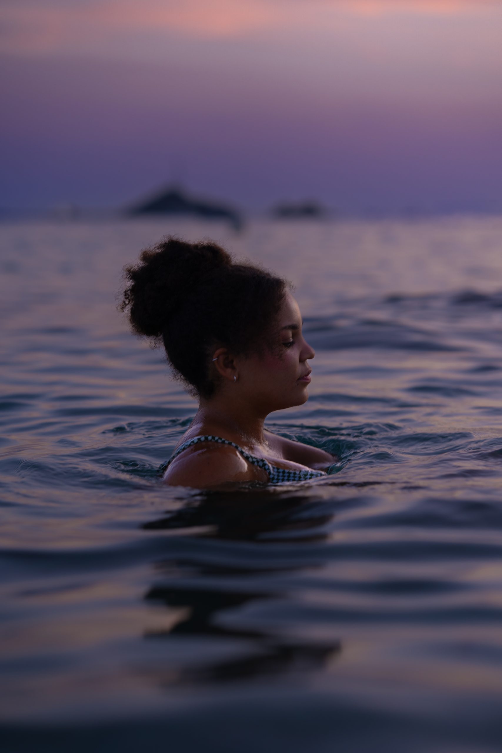 Femme dans la mer au couché de soleil